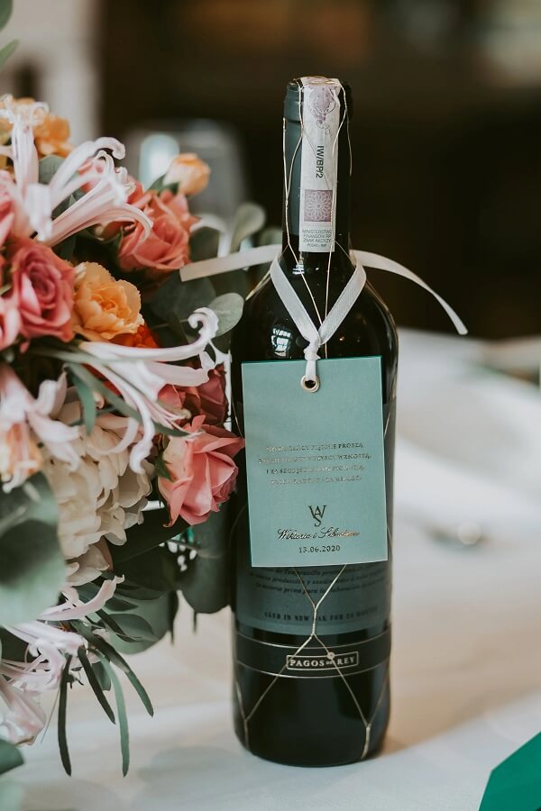 Butelka wina na stole w momencie wesela ozdobne opakoweanie napoju z życzeniami dla gości od panna młodego i panny młodej